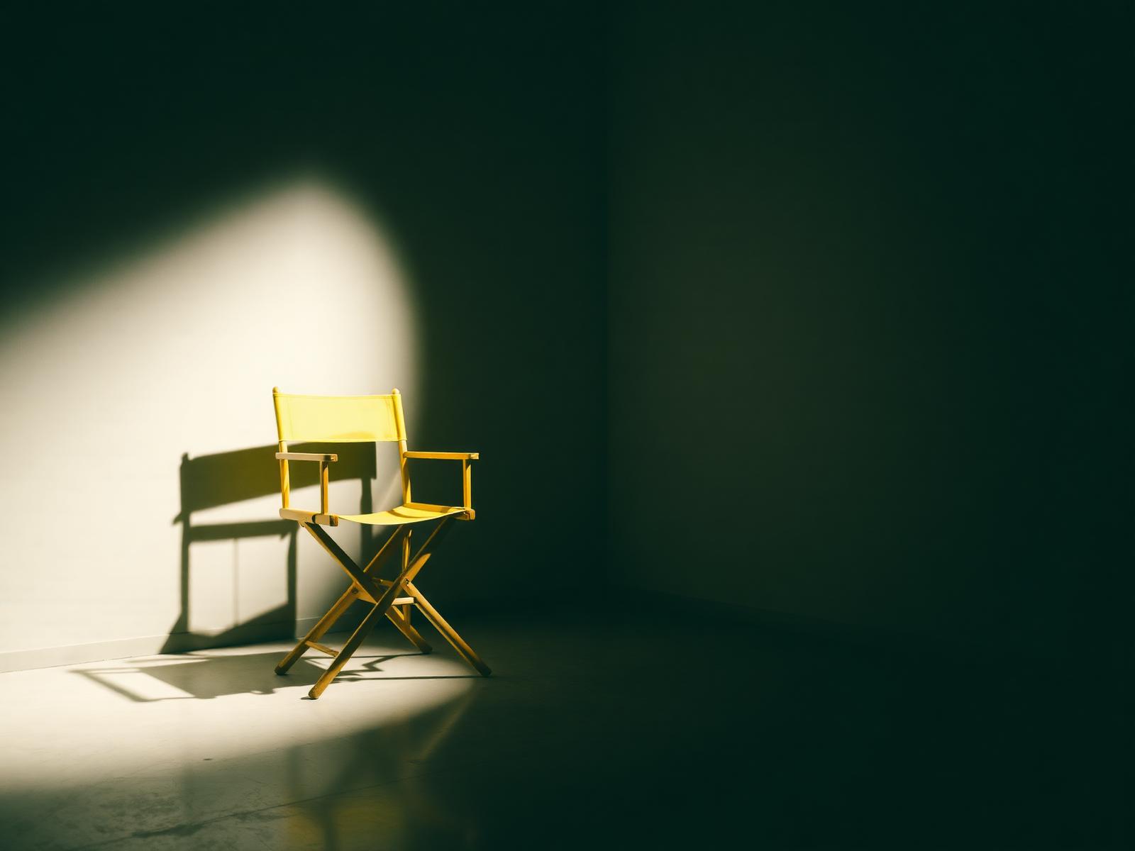 Cadeira de diretor amarela sob spotlight